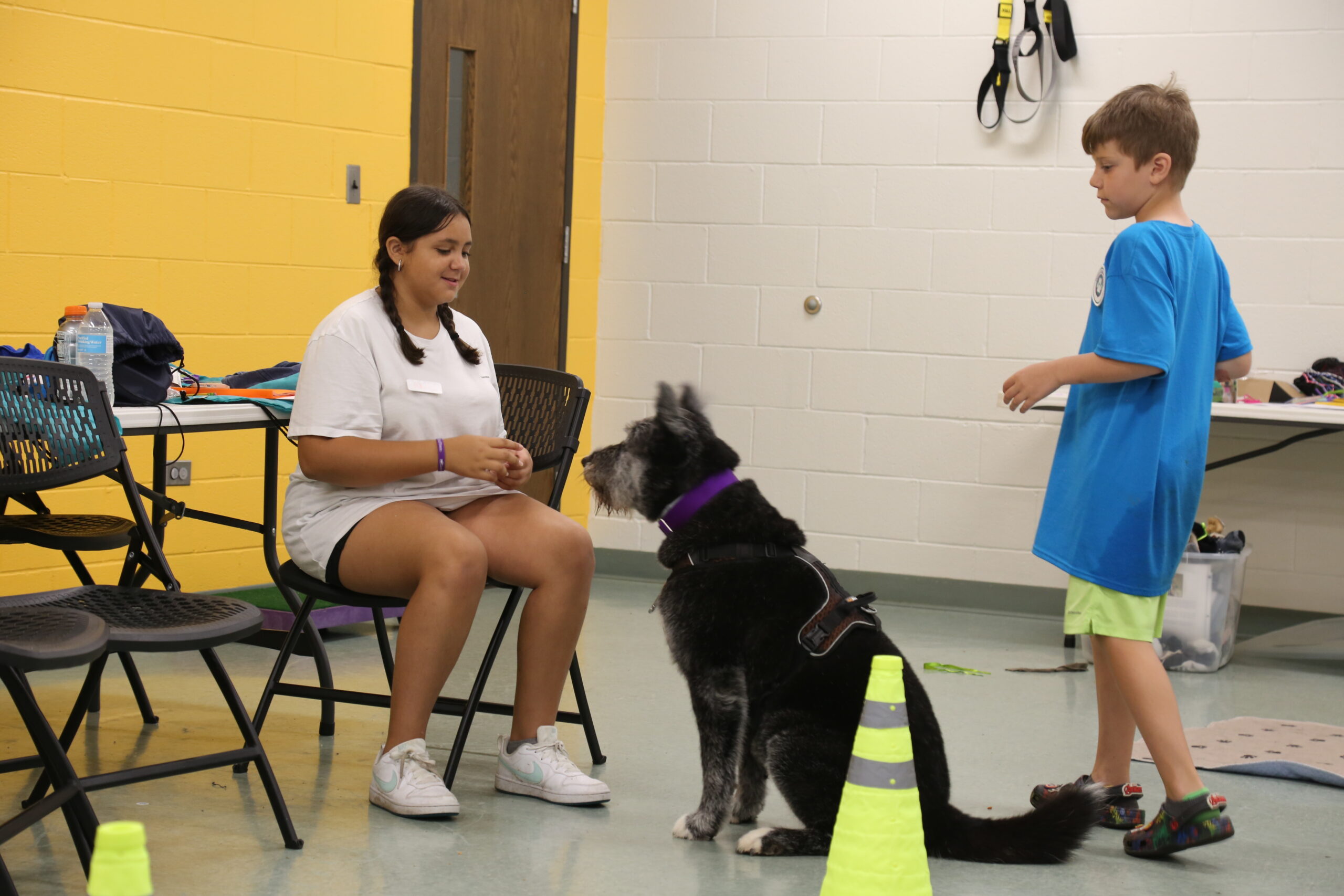 Two Students working with a black dog